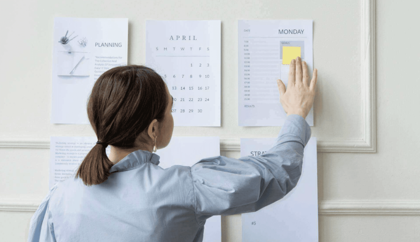 Planner pinning schedule sheets to a wall, representing evaluating and choosing automation software