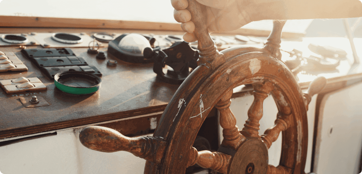 Hands steering a ship’s wheel