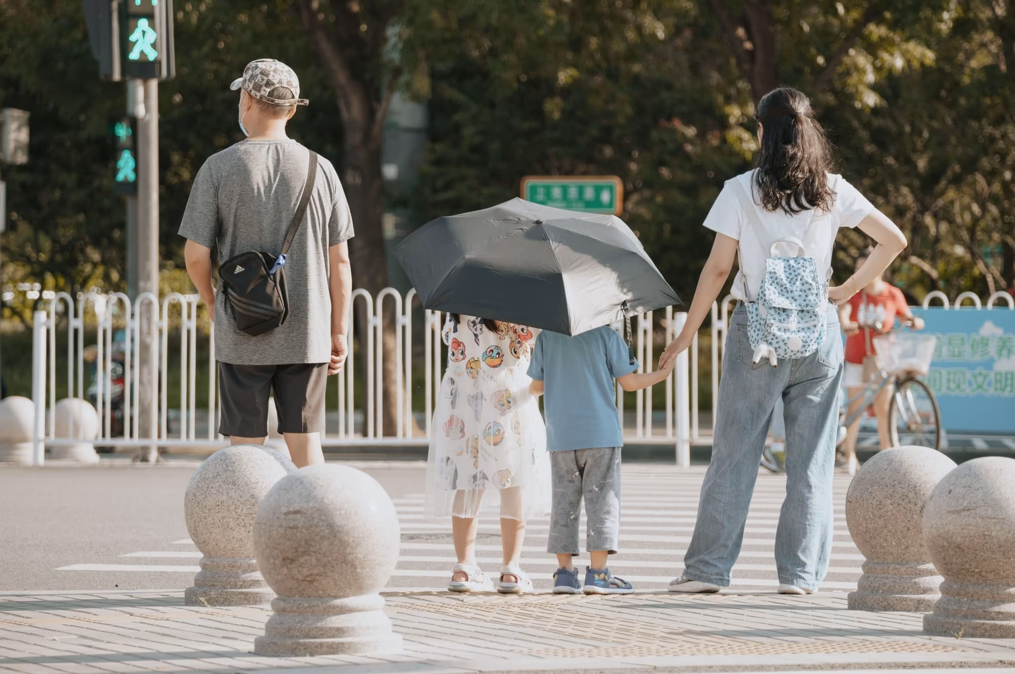 A family holding hands as they wait to cross a city street
